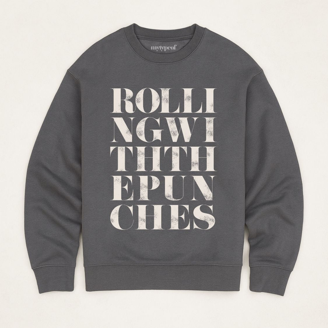 Iron Grey unisex oversized sweatshirt with bold typographic design, 'Rolling with the punches' Photographed as a flay lay on a plain background.