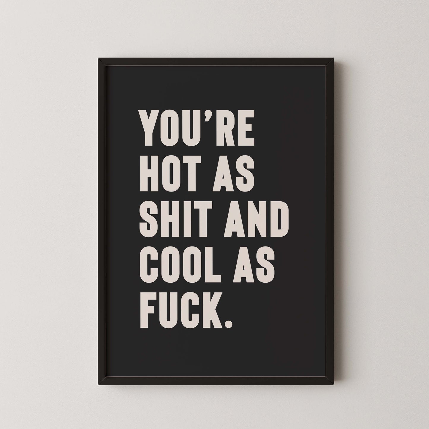 Bold monochrome black and white typography print that reads “You’re hot as shit and cool as f*ck,” styled in a black wooden frame on plain wall.  A cheeky, empowering quote print ideal for renters, couples, or anyone who loves bold graphic art.