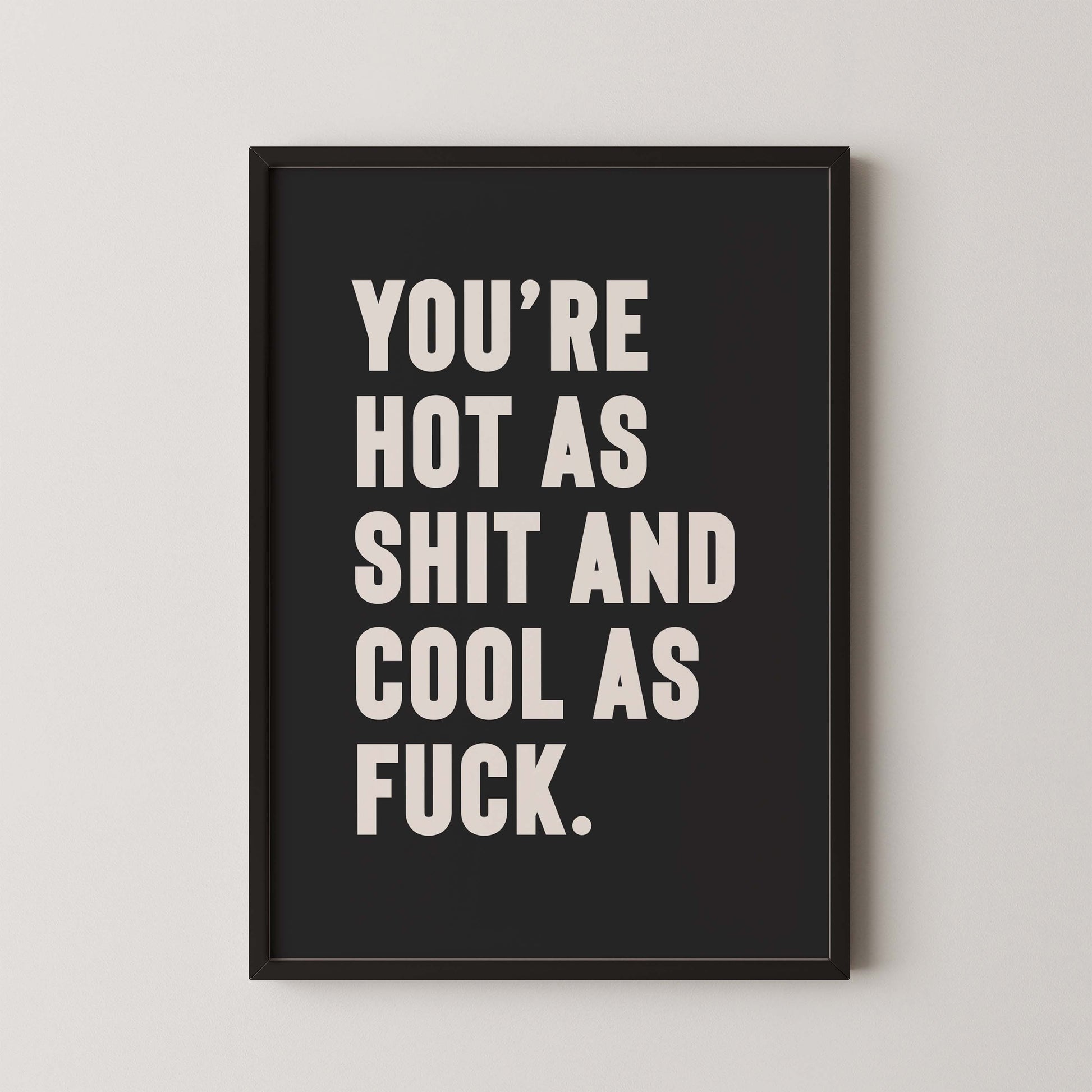 Bold monochrome black and white typography print that reads “You’re hot as shit and cool as f*ck,” styled in a black wooden frame on plain wall.  A cheeky, empowering quote print ideal for renters, couples, or anyone who loves bold graphic art.