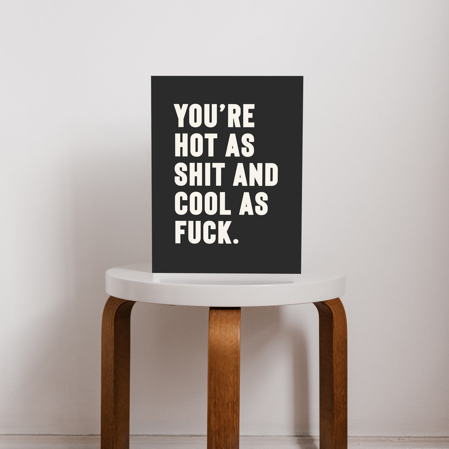 Bold black and white typography print that reads “You’re hot as shit and cool as f*ck,” styled on a stool. A cheeky, empowering quote print ideal for renters, couples, or anyone who loves bold graphic art.