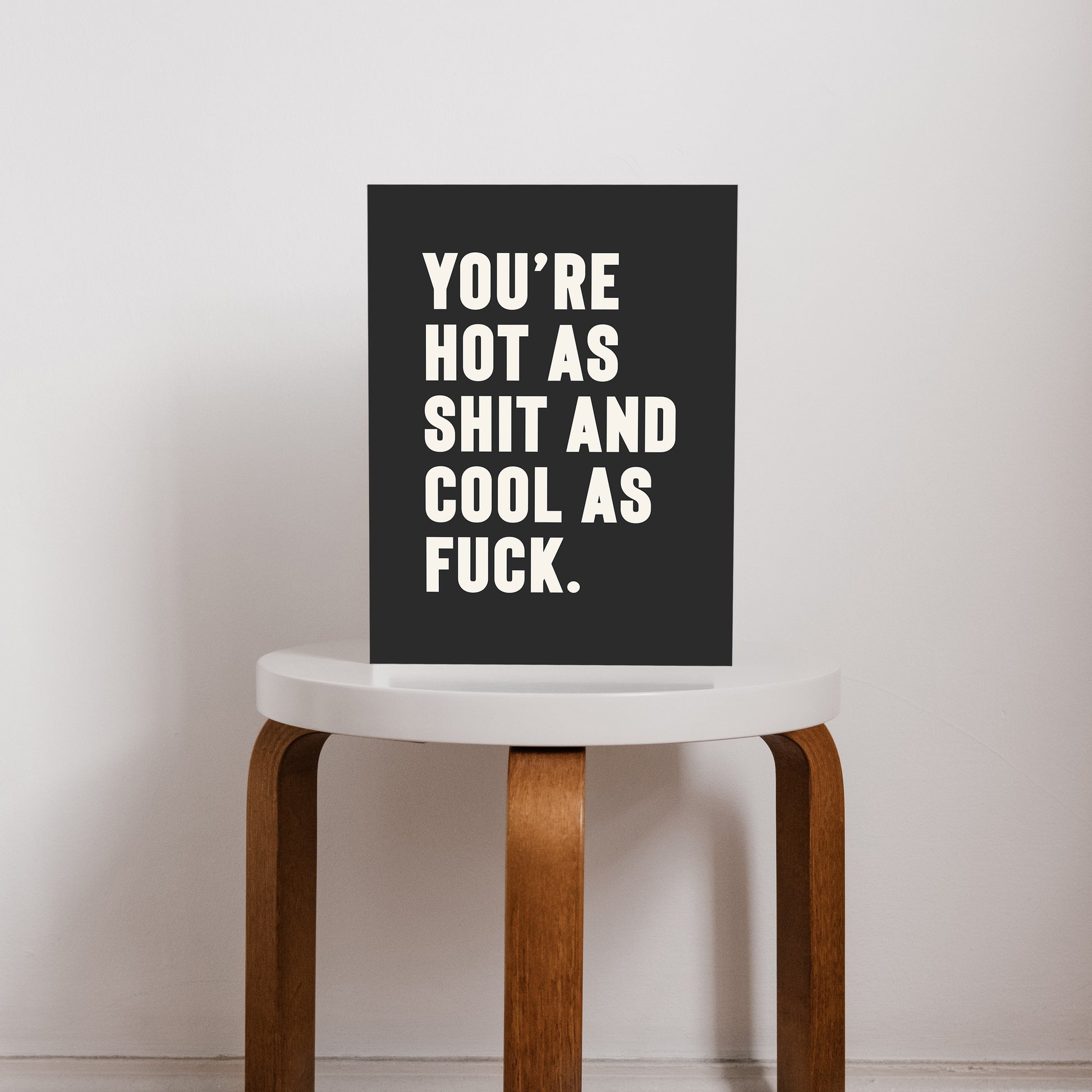 Bold black and white typography print that reads “You’re hot as shit and cool as f*ck,” styled on a stool. A cheeky, empowering quote print ideal for renters, couples, or anyone who loves bold graphic art.