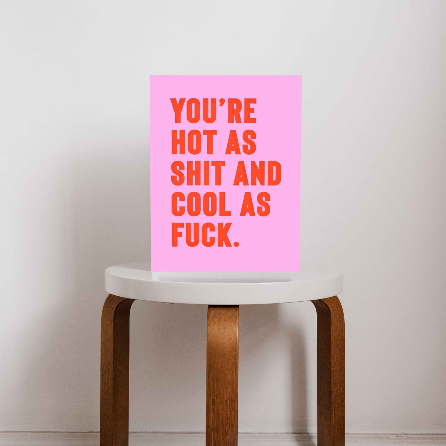 Bold pink and orange typography print that reads “You’re hot as shit and cool as f*ck,” styled on a minimalist stool. A cheeky, empowering quote print ideal for renters, couples, or anyone who loves bold graphic art.