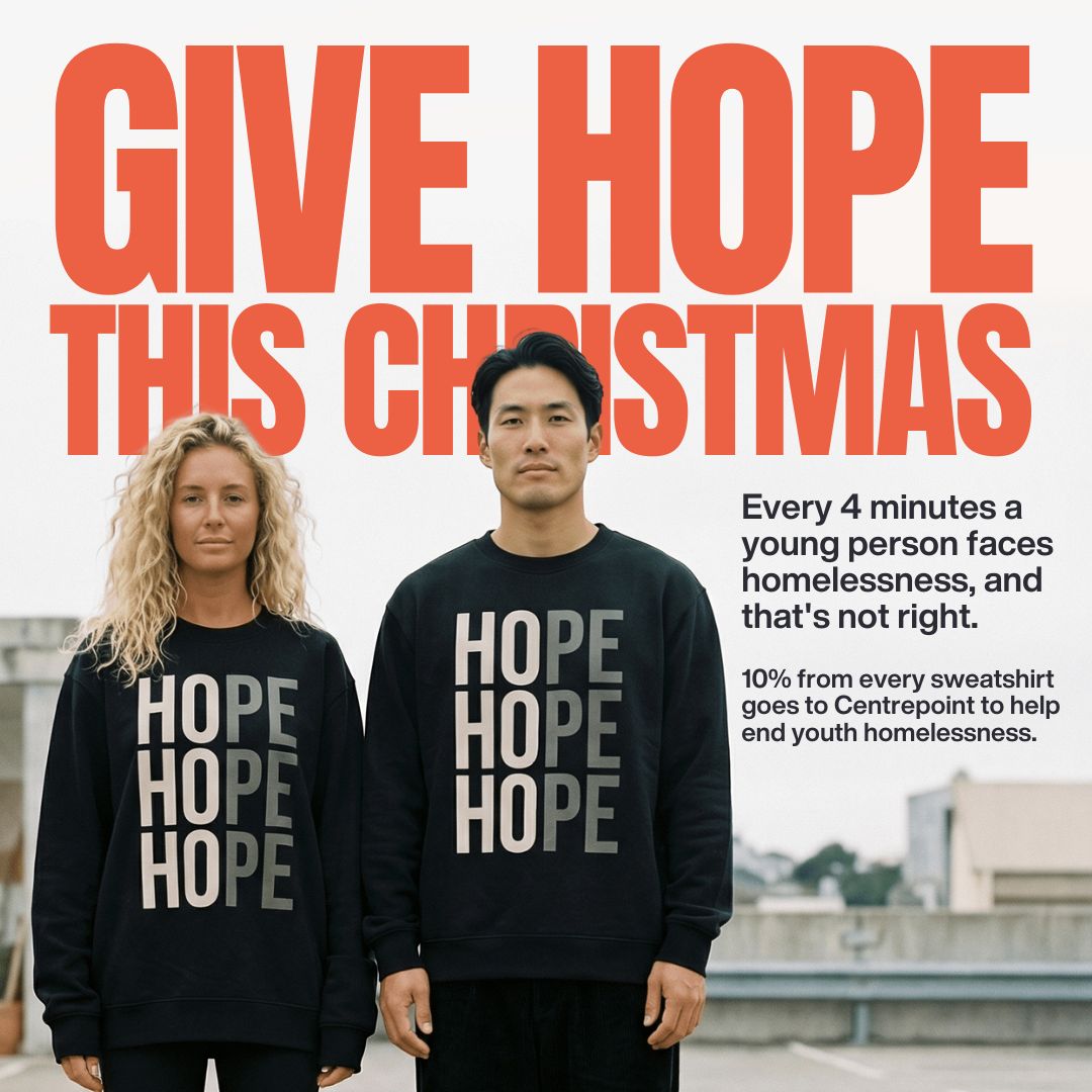 Couple wearing black HOPE sweatshirts, with the text Give Hope This Christmas behind them. 