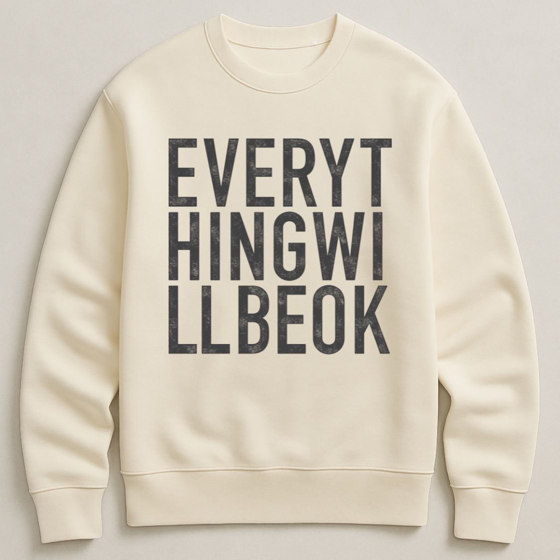 Ivory oversized, organic unisex sweatshirt with bold vintage style typography in black saying "Everything will be ok"  Photographed  as a flay lay on a plain background. 