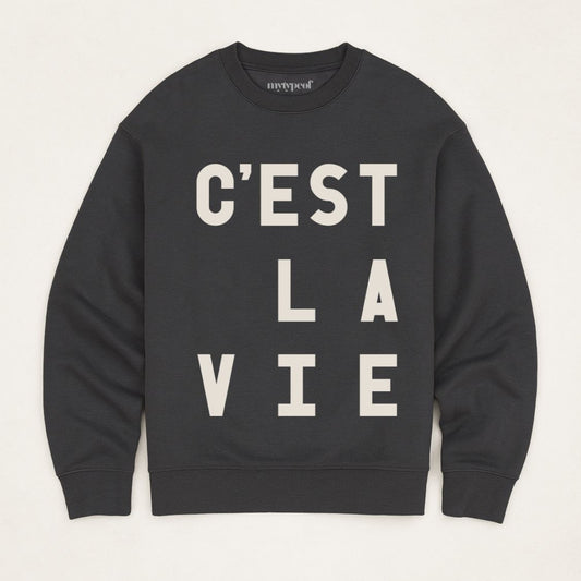 Black, typographic sweatshirt, with 'C'est La Vie' design. unisex, oversized sweatshirt, photographed  as a flay lay on a plain background. 