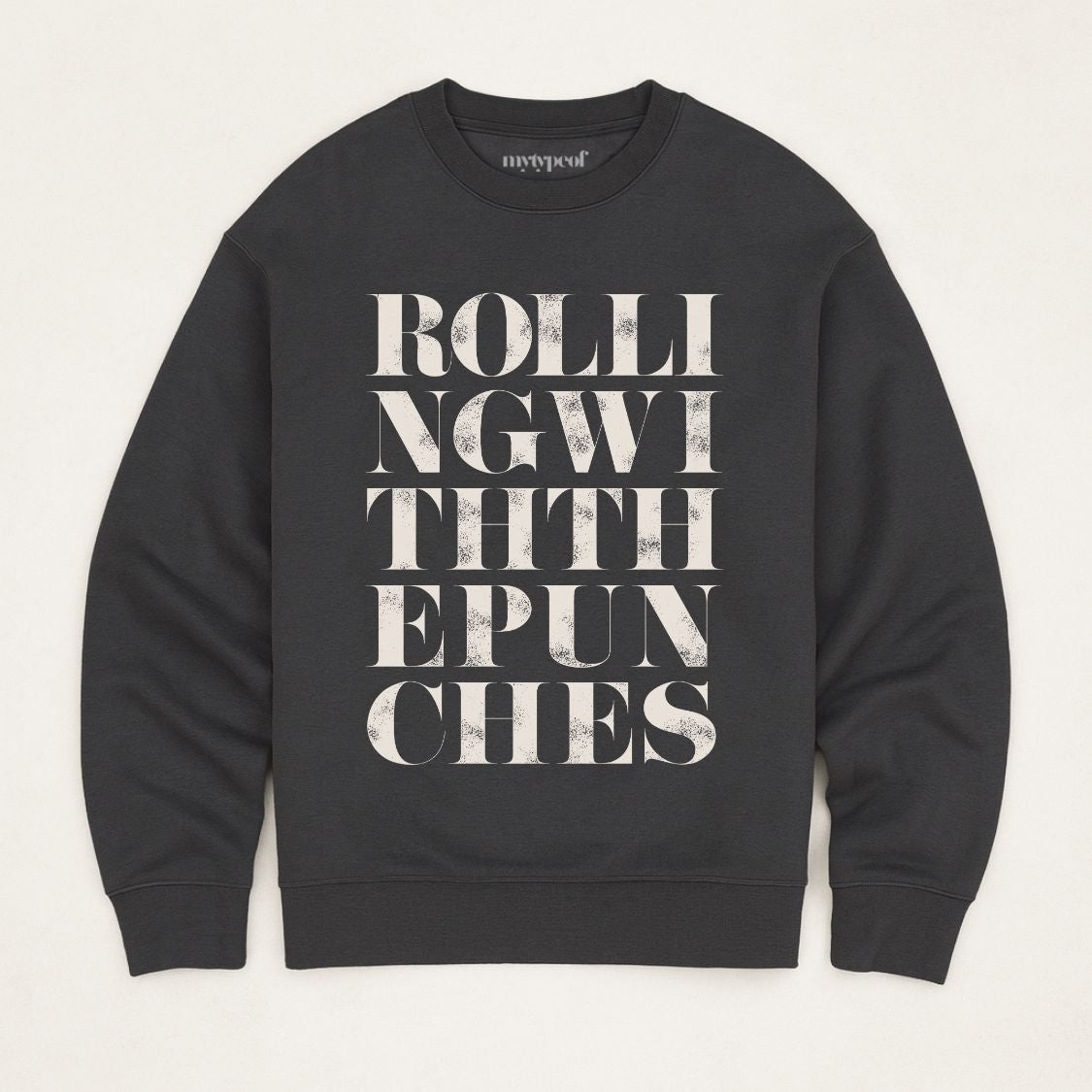 Black unisex oversized sweatshirt with bold typographic design, 'Rolling with the punches' Photographed  as a flay lay on a plain background. 