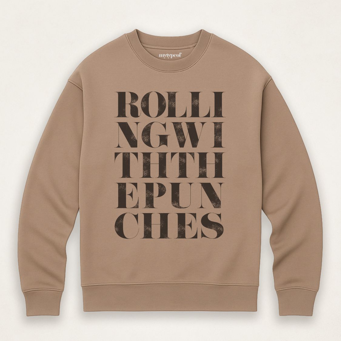 Caramel colour unisex oversized sweatshirt with bold typographic design, 'Rolling with the punches' Photographed  as a flay lay on a plain background. 