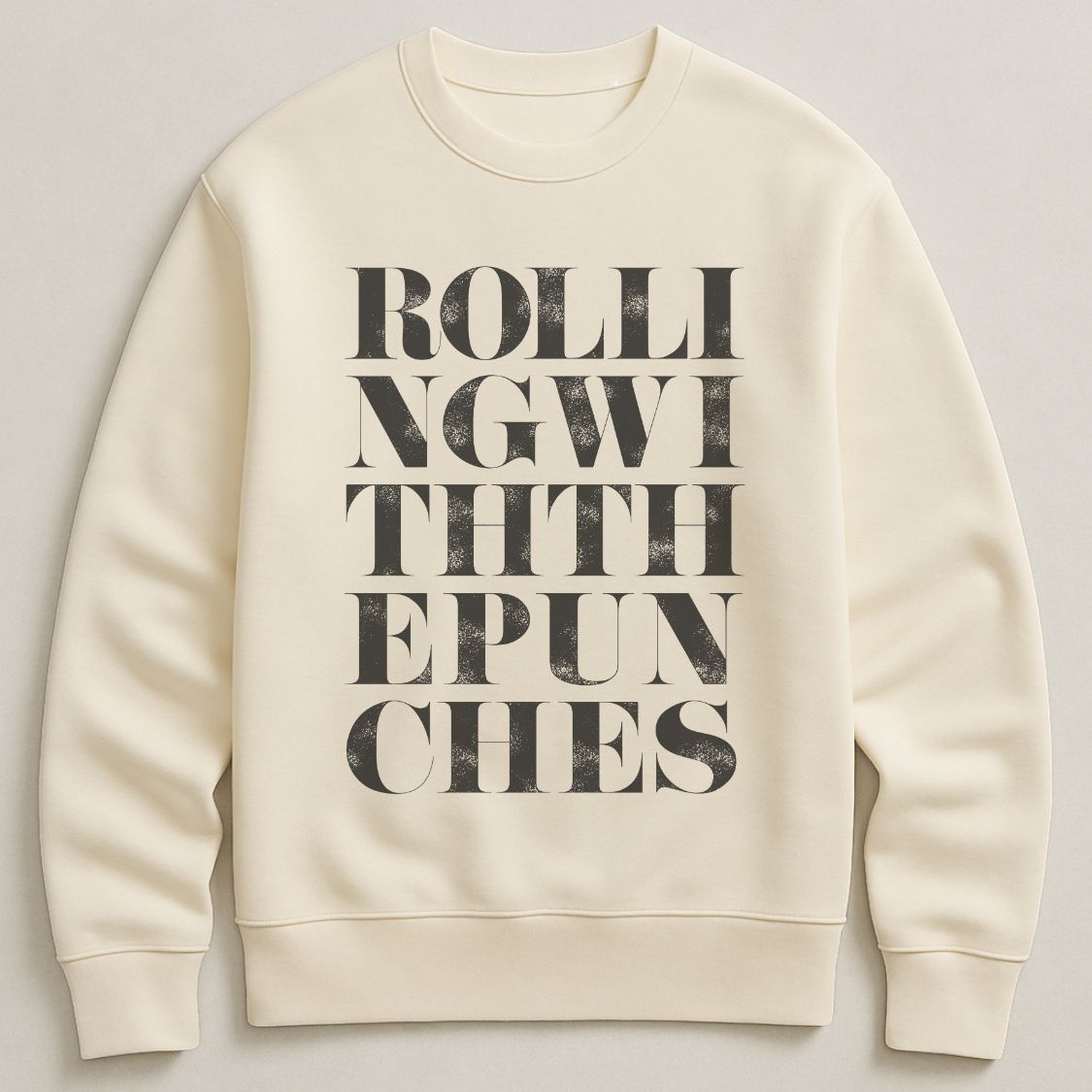 Ivory colour unisex oversized sweatshirt with bold typographic design, 'Rolling with the punches' Photographed  as a flay lay on a plain background. 