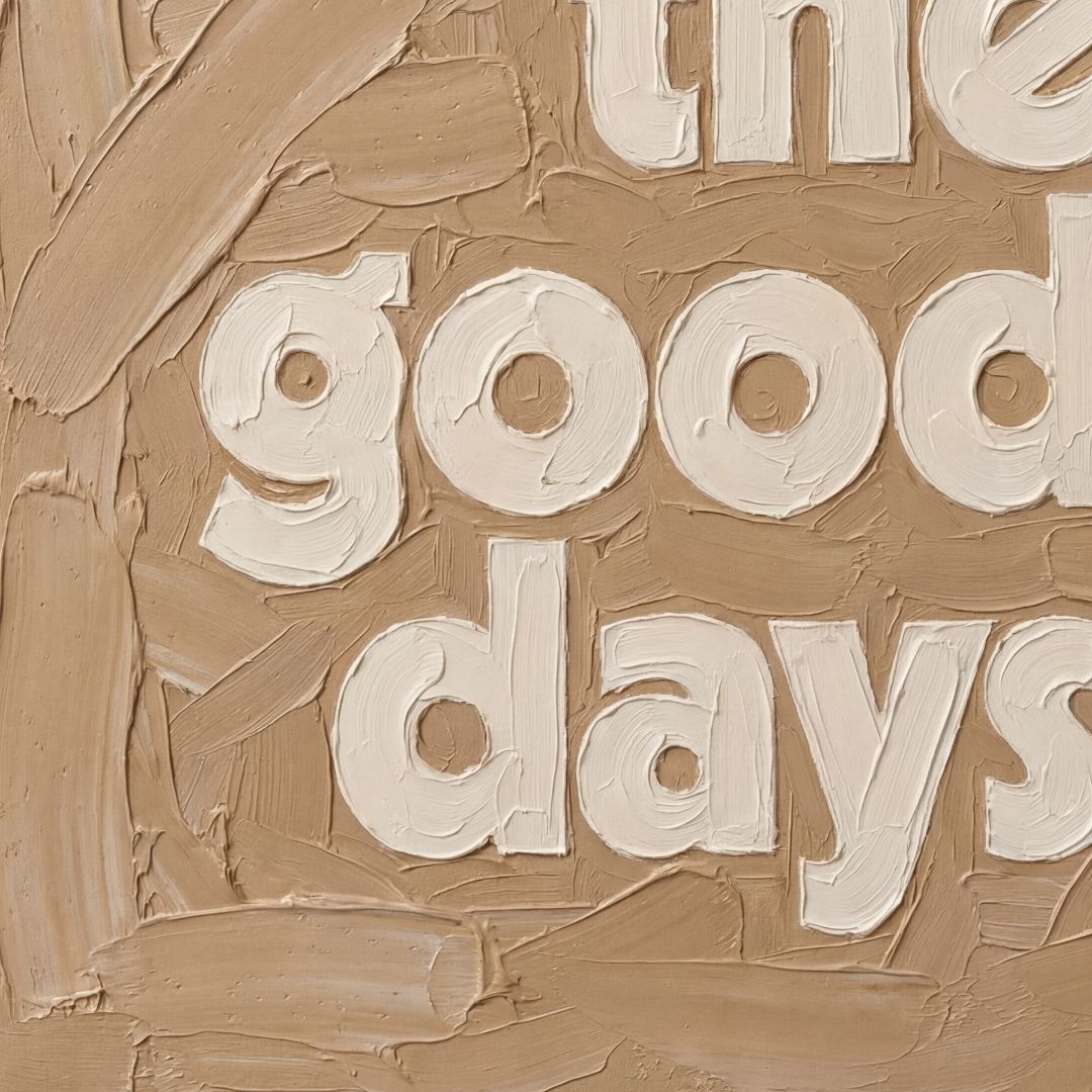 Close-up of textured oil-style typography showing thick brush strokes and layered paint detail in caramel and cream. These are the good days quote. 
