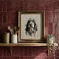 Painted pet portrait in gold frame displayed on shelf against red tiled wall