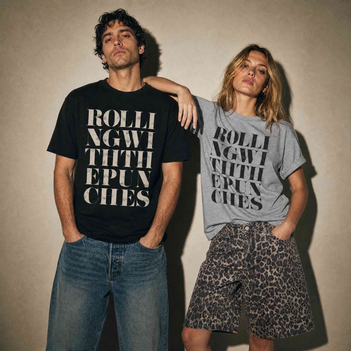 Man wearing black t-shirt with vintage distressed letters saying Rolling with the punches. Woman wearing grey tshirt, with black letters, same quote, styled with leopard print jorts