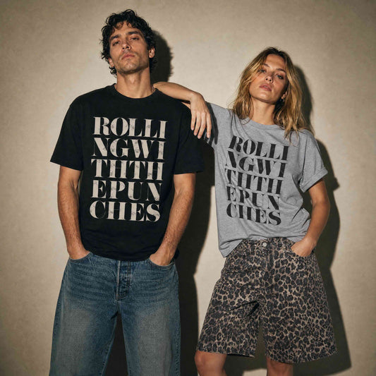 Man wearing black t-shirt with vintage distressed letters saying Rolling with the punches. Woman wearing grey tshirt, with black letters, same quote, styled with leopard print jorts