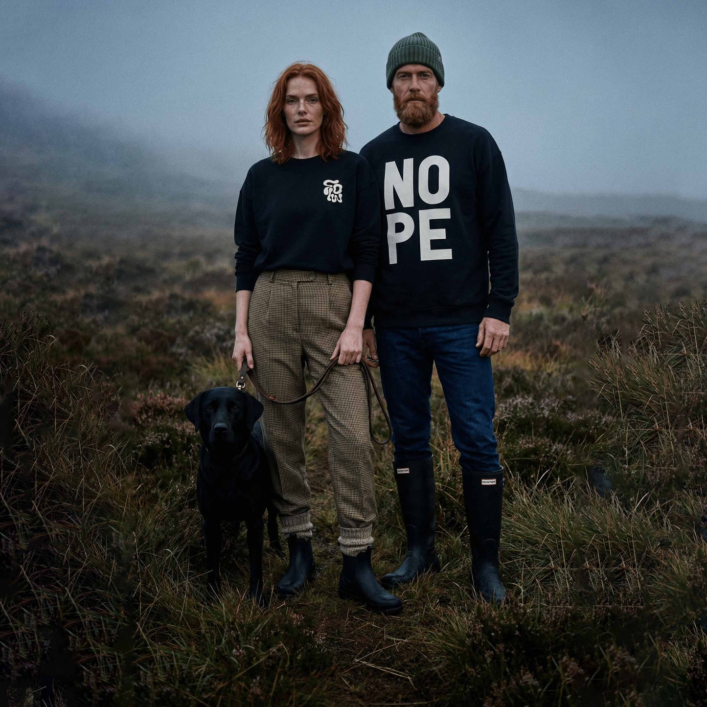 Couple in highlands with dog wearing Flowsweatshirt, and Nope Sweatshirt in black. 