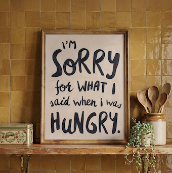 "Sorry for what I said when I was hungry" oil painted kitchen wall art print, displayed on shelf against mustard tiles. 