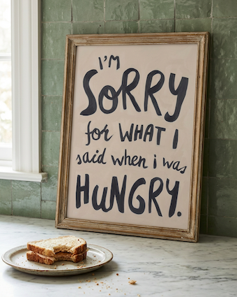 Funny wall art quote next to a half eaten sandwhich.  Hangry wall art print, soft oil painted letters in charcoal colour on stone background.  Quote says "I'm sorry for what I said when I was hungry"