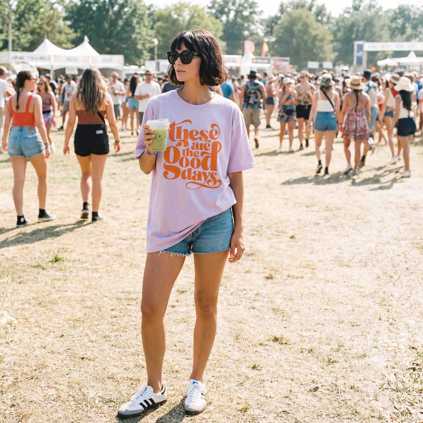Woman wearing lavender “These Are the Good Days” slogan t-shirt with denim shorts at outdoor festival