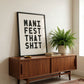 Framed Manifest That Shit motivational typography print displayed on a mid-century sideboard with houseplant.
