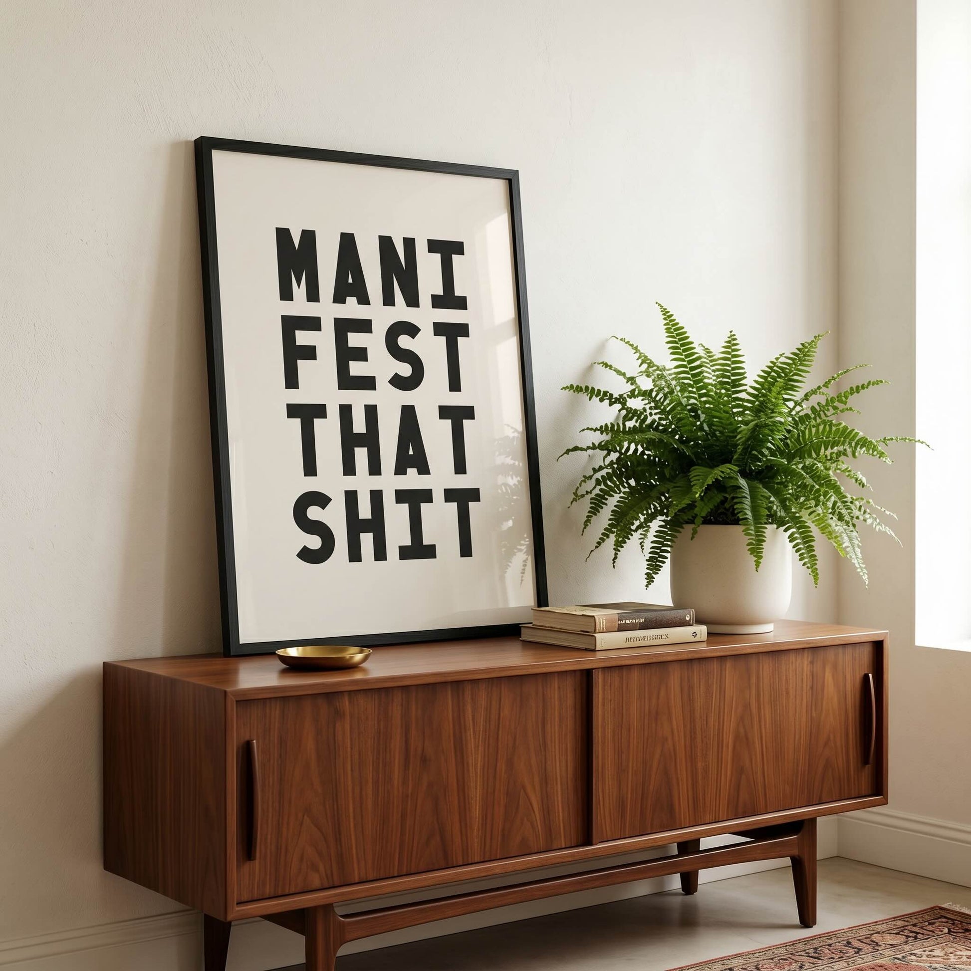 Framed Manifest That Shit motivational typography print displayed on a mid-century sideboard with houseplant.