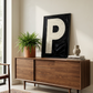 Letter P oil paint art print framed in black styled on   a mid century sideboard interior with large window