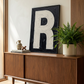 Letter R oil paint art print framed in black styled on   a mid century sideboard interior with large window