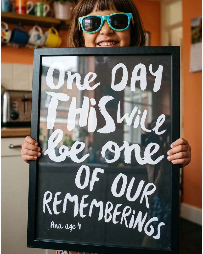 Little girl with sunglasses holding a framed black and white custom made quote print of her quote: One days this will be one of our rememberings