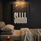 Bohemium styled bedroom with wall light on illuminating  art print in oil paint saying Shhhh in black and white, framed in wood. 