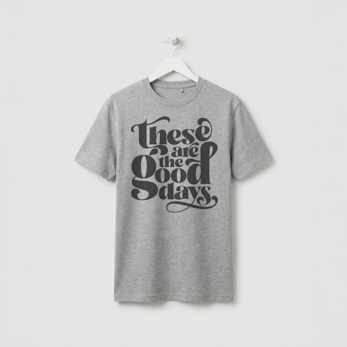 Greay Marl  “These Are the Good Days” graphic t-shirt on white wooden hanger, minimalist studio background