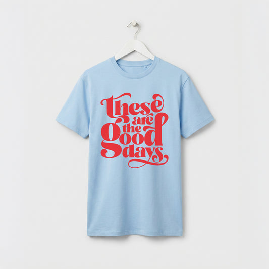 Light Blue and red “These Are the Good Days” graphic t-shirt on white wooden hanger, minimalist studio background