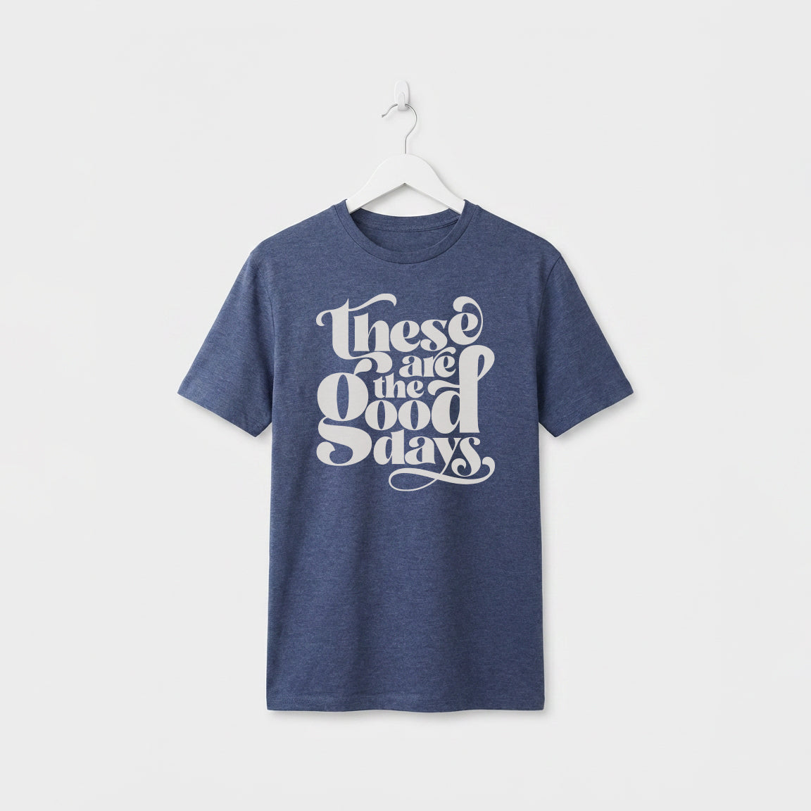 Navy Marl“These Are the Good Days” graphic t-shirt on white wooden hanger, minimalist studio background
