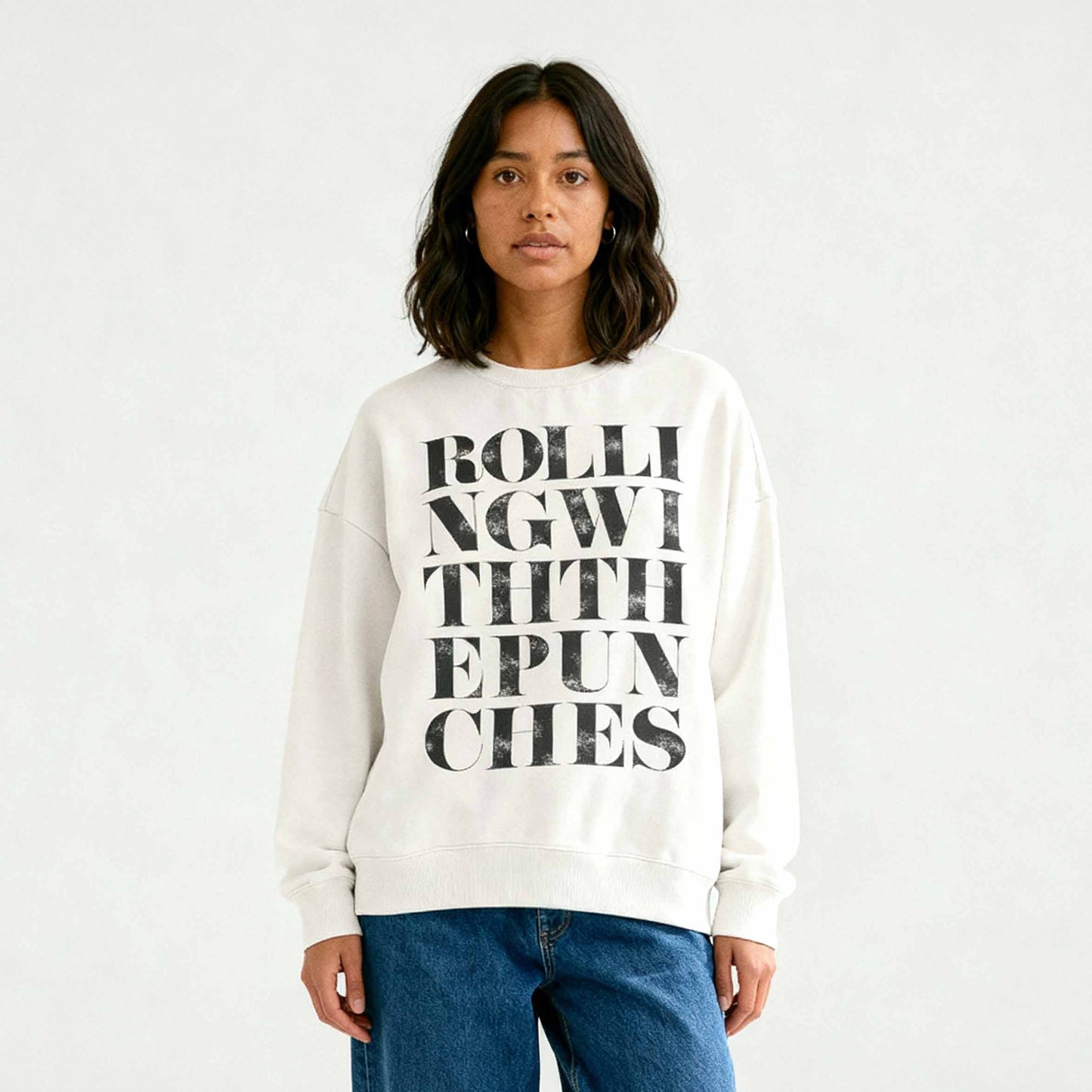 Ivory coloured oversized sweatshirt with Rolling With The Punches typography design styled with jeans on latina model. 