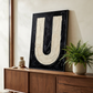 Letter U oil paint art print framed in black styled on   a mid century sideboard interior with large window
