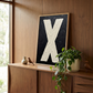 Letter X oil paint art print framed in wood styled on   a mid century sideboard interior with large window