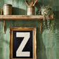 Letter Z oil paint art print framed in a vintage gold frame, on a shelf against  green zellige tiled kitchen