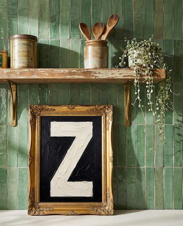 Letter Z oil paint art print framed in a vintage gold frame, on a shelf against  green zellige tiled kitchen