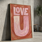 Love U typography created in oil paint, in pinks and orange, framed in brass leaning agaist a concrete  wall. 