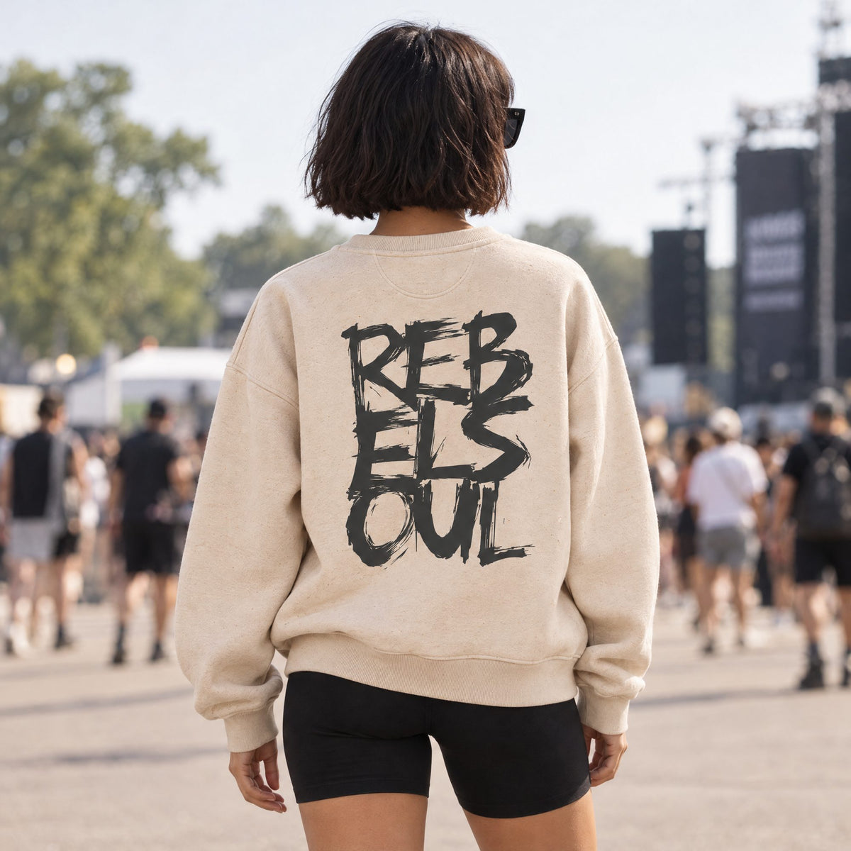 Back view of a woman at a festival wearing the Rebel Soul organic sweatshirt in raw natural, by Burnt Peach